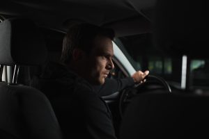 serious male private detective doing surveillance from his car